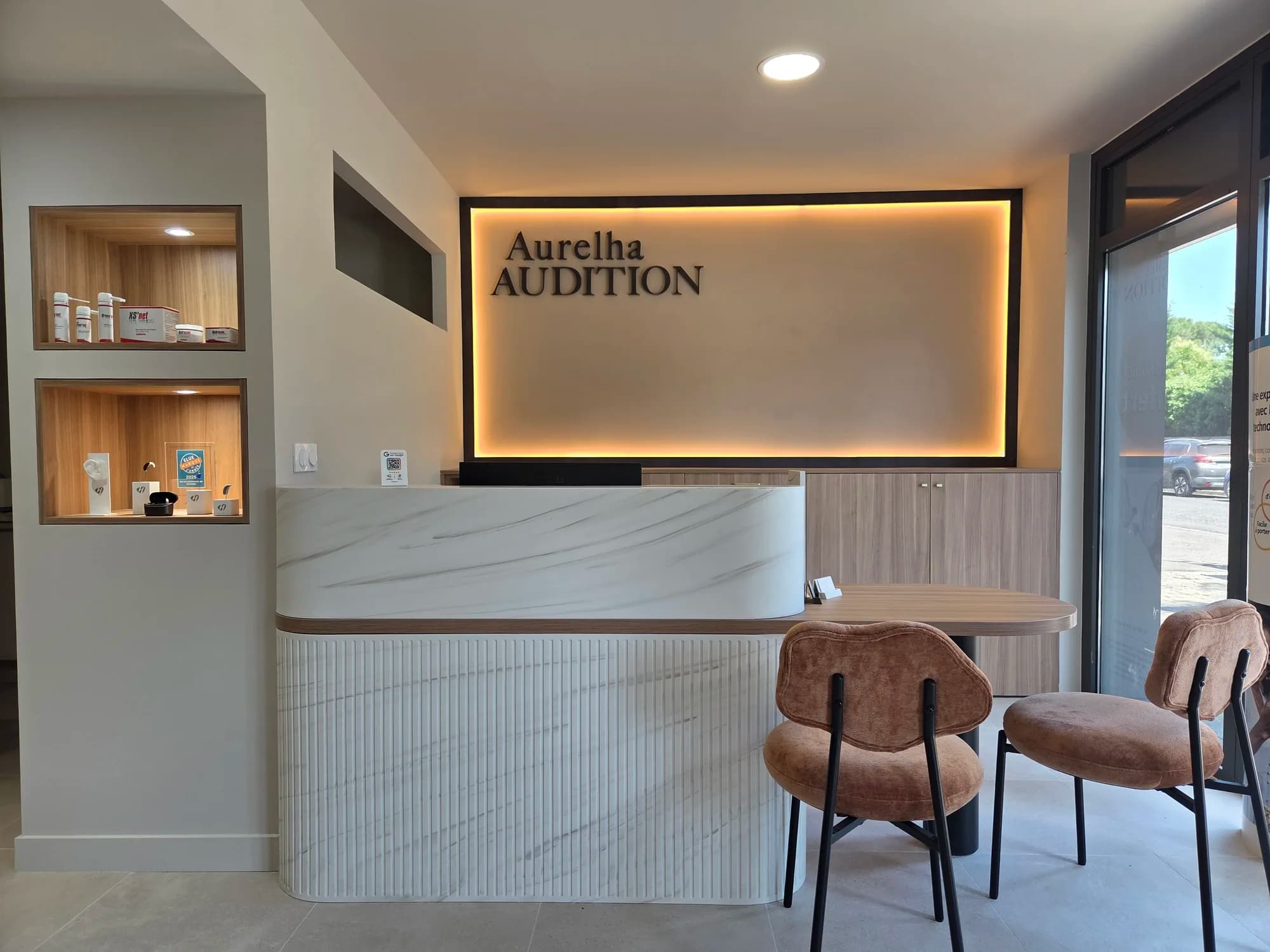 L’accueil du centre Aurelha Audition à Baillargues : comptoir en marbre et enseigne lumineuse.